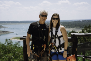 Adventurers ready to zipline, posing with scenic Lake Travis behind them.