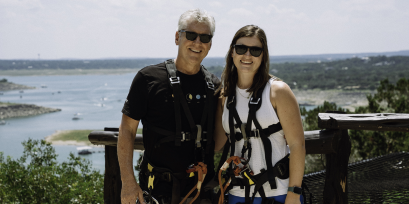 Adventurers ready to zipline, posing with scenic Lake Travis behind them.