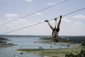 Zipliner on the line upside down smiling.
