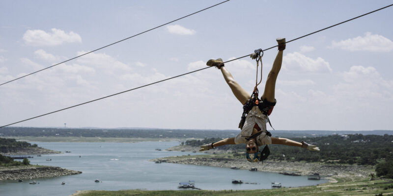 Zipliner on the line upside down smiling.