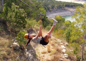 Zipline smiling as they go down the line of majesty over lake Travis