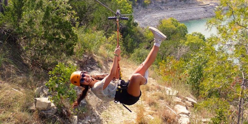 Zipline smiling as they go down the line of majesty over lake Travis