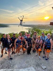 Group of Zippers in front of zipline overlooking the lake.