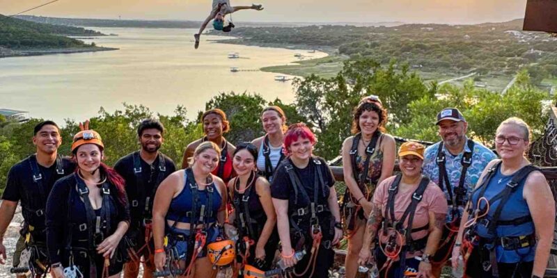 Group of Zippers in front of zipline overlooking the lake.